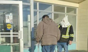 Un homme portant une capuche à la KKK devant un bureau de poste