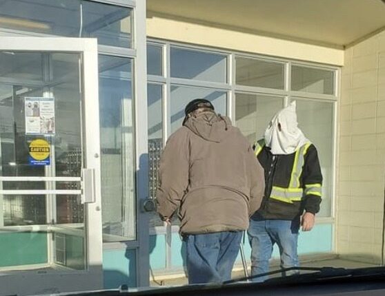Un homme portant une capuche à la KKK devant un bureau de poste
