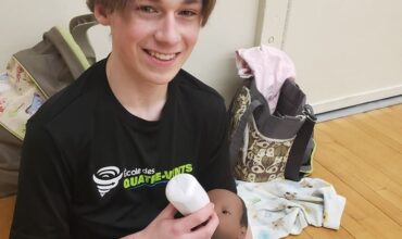 Un adolescent tenant un bébé-robot