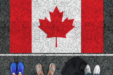 Un drapeau canadien dessiné au sol avec trois paires de pieds, en sandales et deux paires de baskets